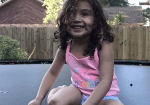 A little girl sitting on a trampoline.