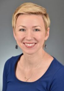 A smiling woman in a blue top.