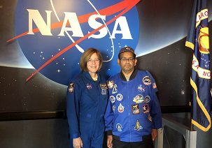 Two people standing in front of a nasa sign.