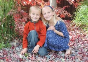 Two children posing for a photo in a garden.