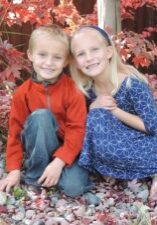 Two children posing for a photo in a garden.