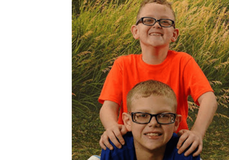 Two boys are posing for a photo in a field.