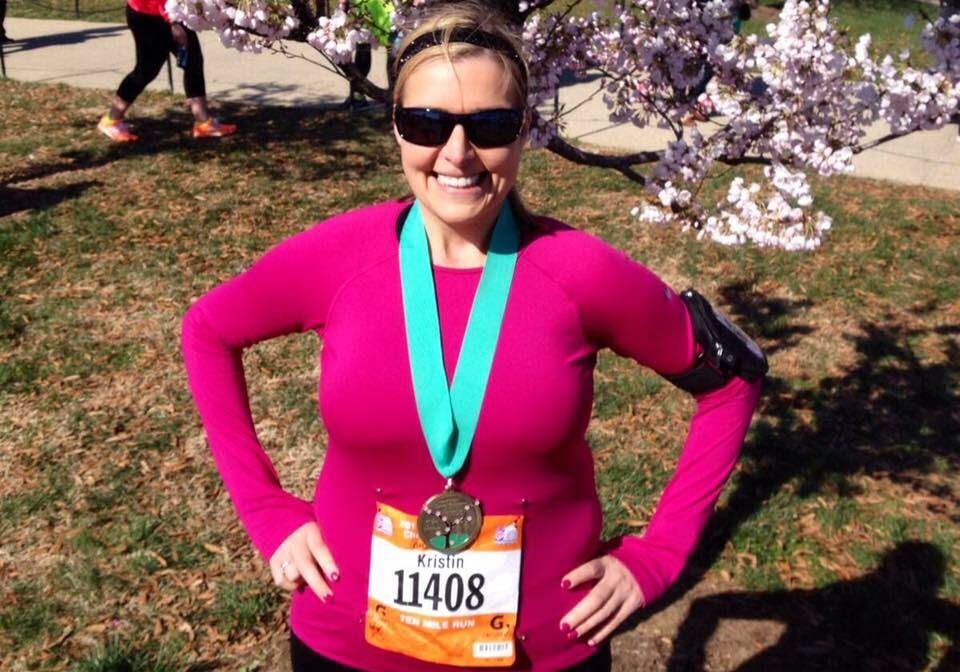 A woman standing in front of a tree with a medal.