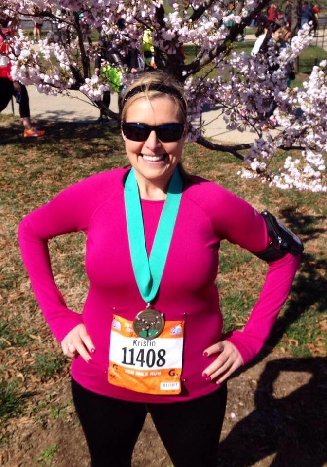 A woman standing in front of a tree with a medal.