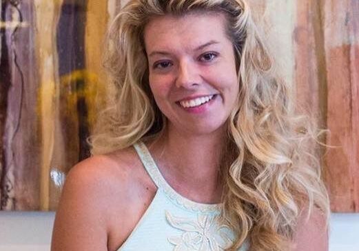 A blonde woman smiling in front of a painting.