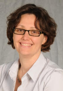 A woman wearing glasses and a white shirt.