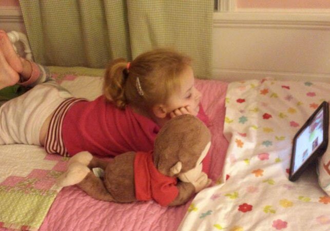 A girl laying on a bed with a teddy bear.