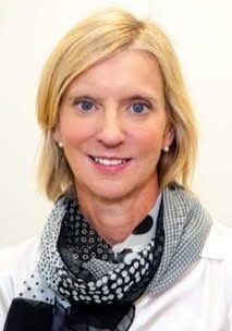 A woman in a white shirt with a black and white scarf.