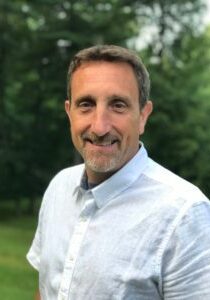 A man in a white shirt standing in a field.